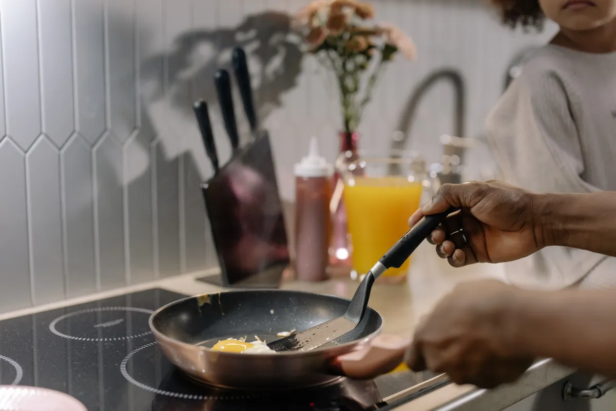 Huevos friéndose sobre una placa de inducción durante la preparación del desayuno