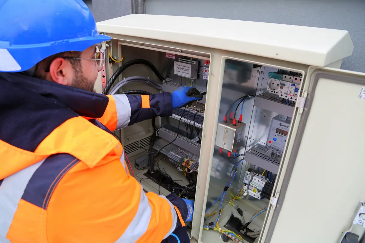 Ingeniero con equipo de protección trabajando en un cuadro eléctrico exterior
