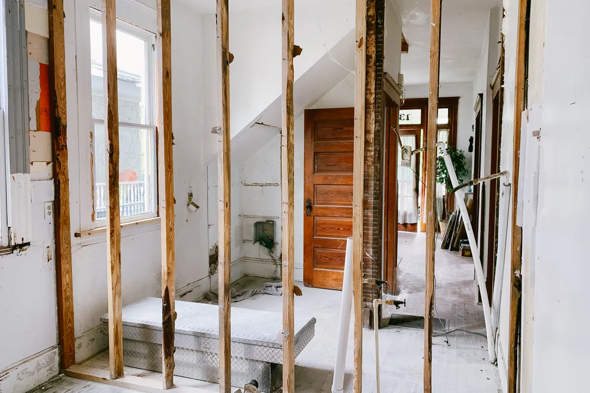 Interior de una vivienda en reforma con vigas de madera vistas y una puerta