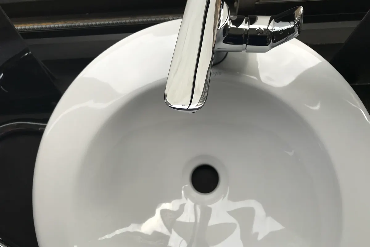 Lavabo blanco visto desde arriba, con el grifo cromado y el desagüe en el centro