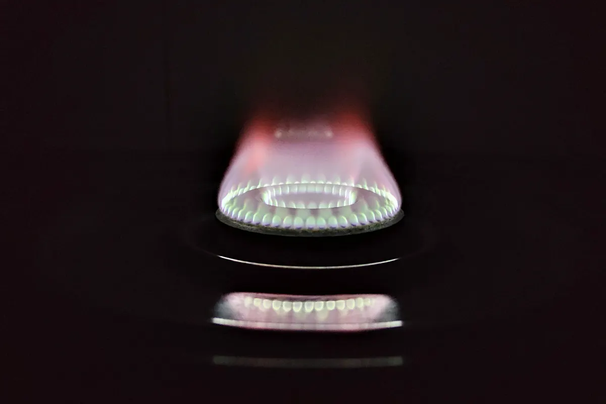 Llama de una cocina de gas brillando sobre un fondo oscuro