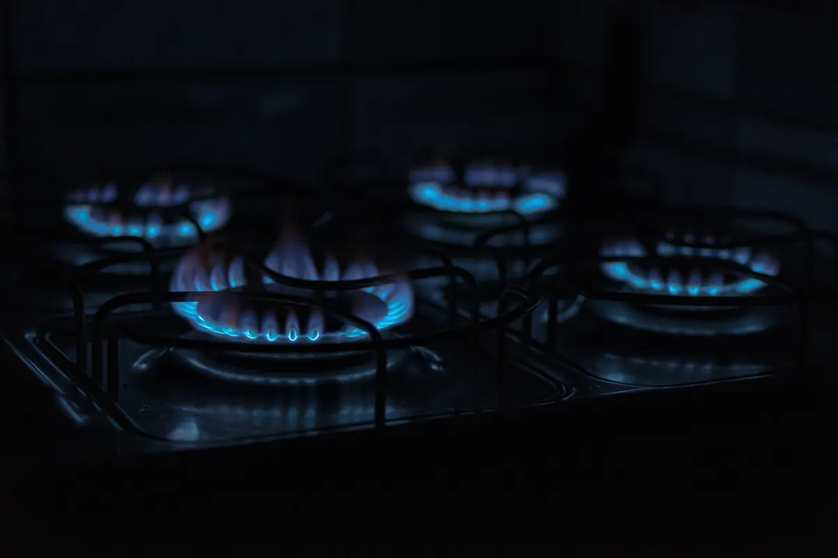 Llamas azules de los quemadores de una cocina de gas en penumbra