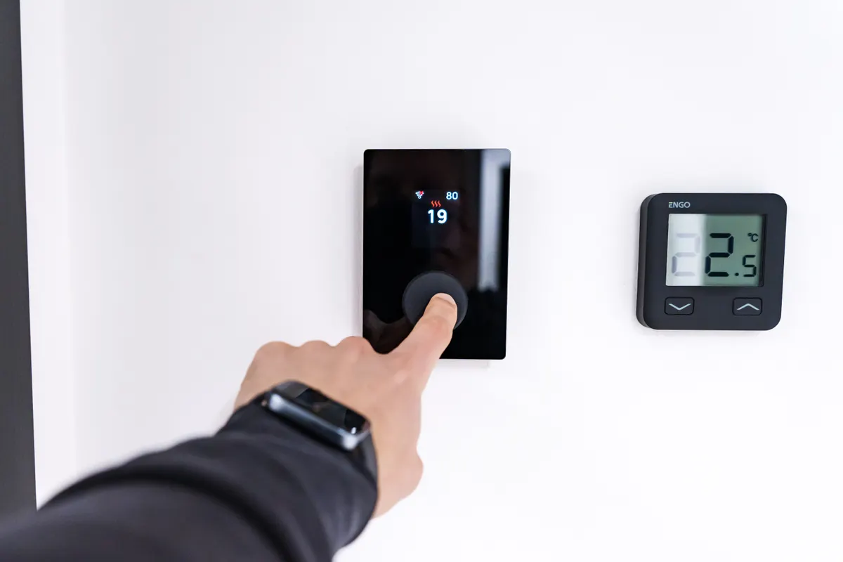 Mano ajustando un termostato digital en una vivienda moderna