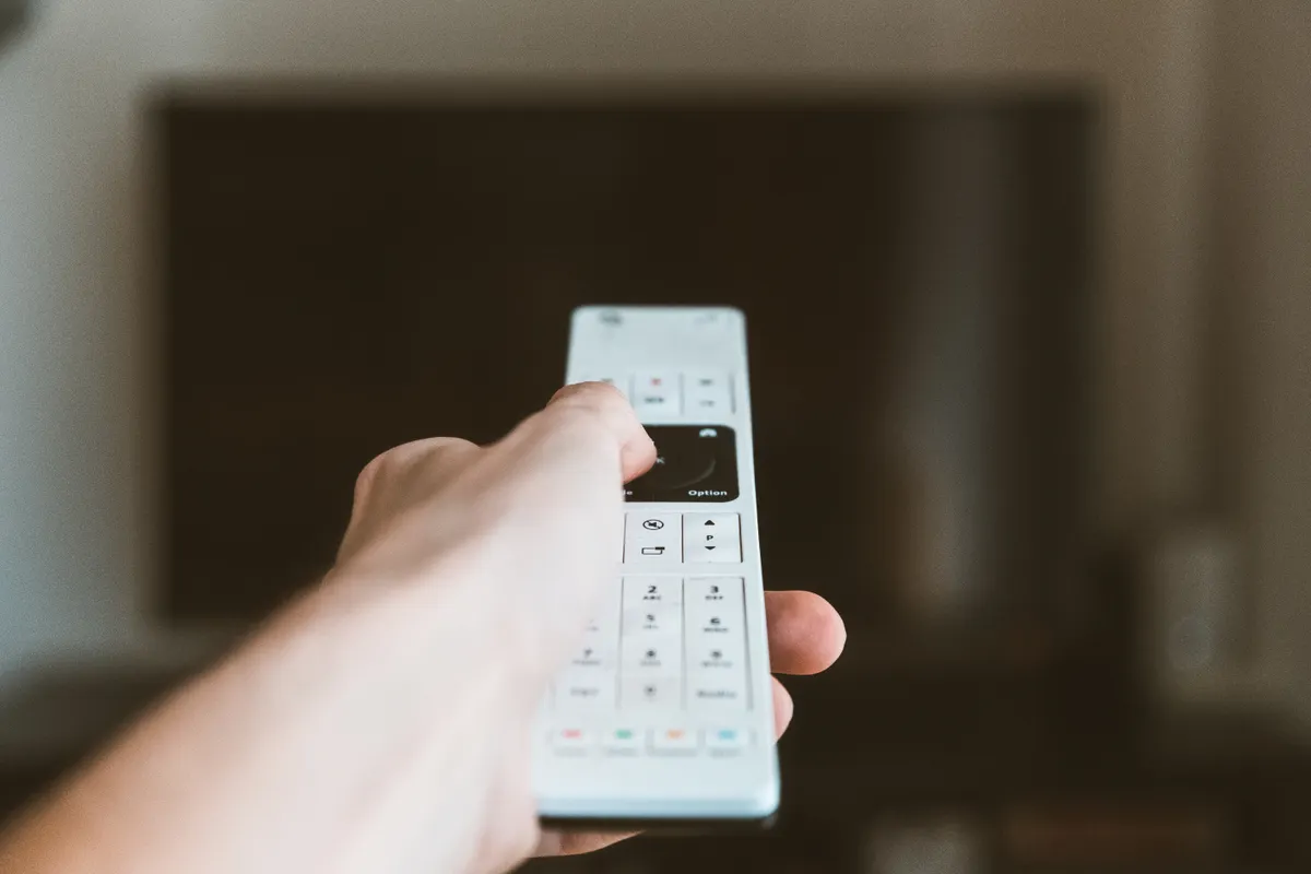 Mano usando el mando a distancia para manejar un televisor