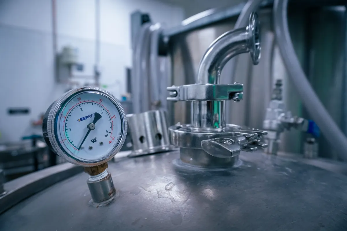 Manómetro de presión sobre un depósito de acero inoxidable en una instalación industrial