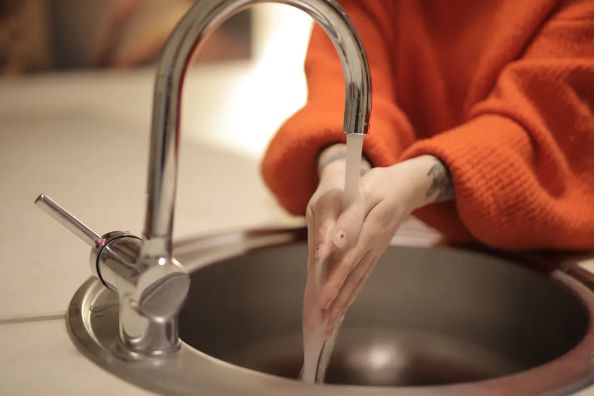 Manos lavándose bajo el agua del grifo en un lavabo