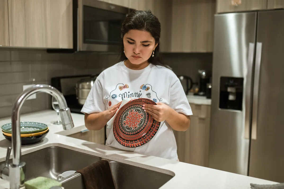 Mujer joven secando un plato en una cocina de diseño