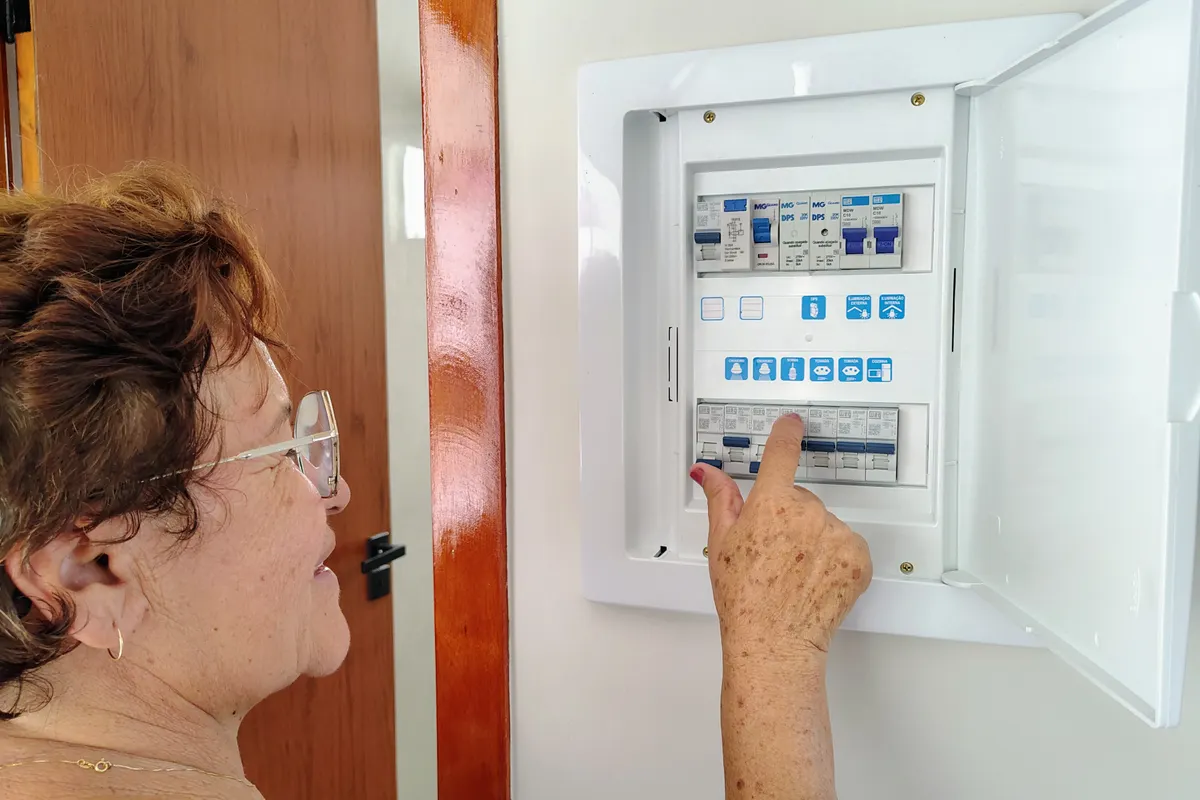 Mujer mayor accionando un cuadro de fusibles en casa