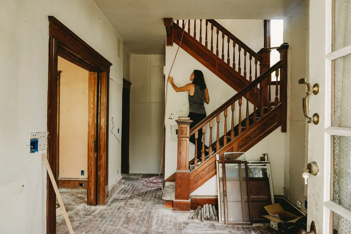 Mujer trabajando en la reforma de una casa con una escalera de madera