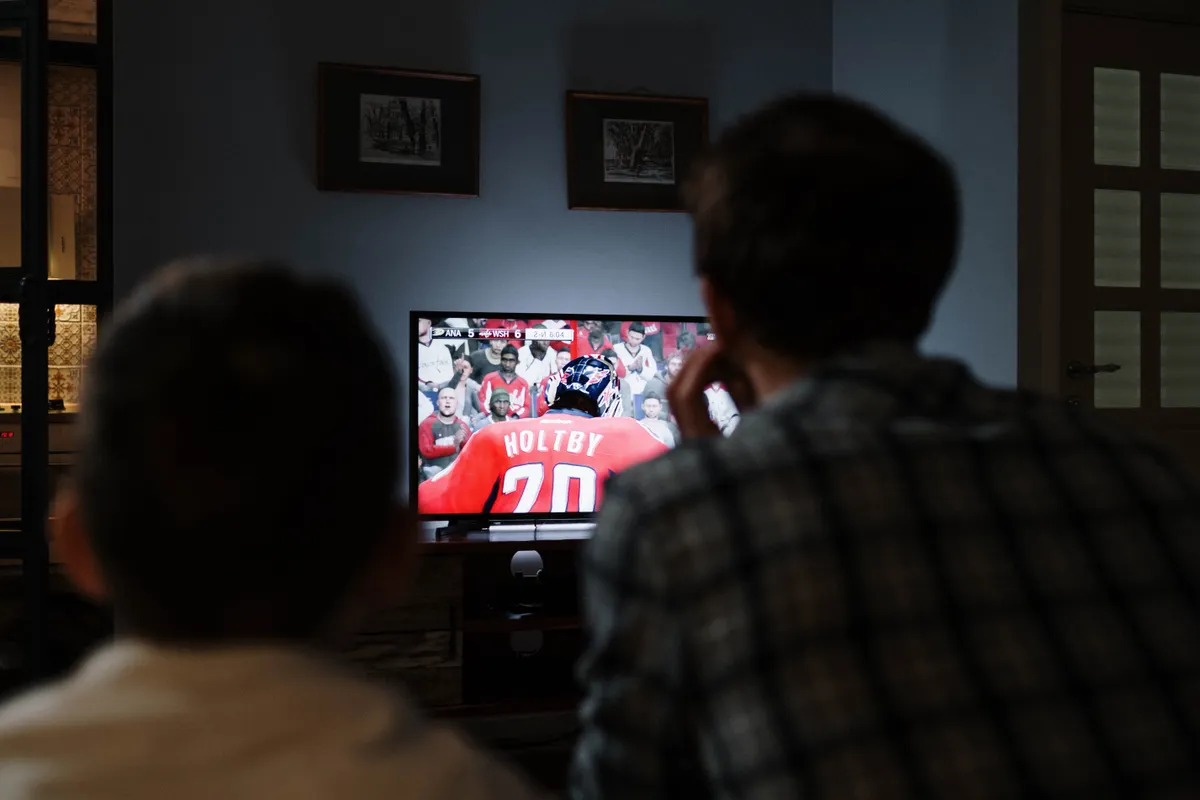 Padre e hijo viendo juntos un partido de hockey en la televisión del salón