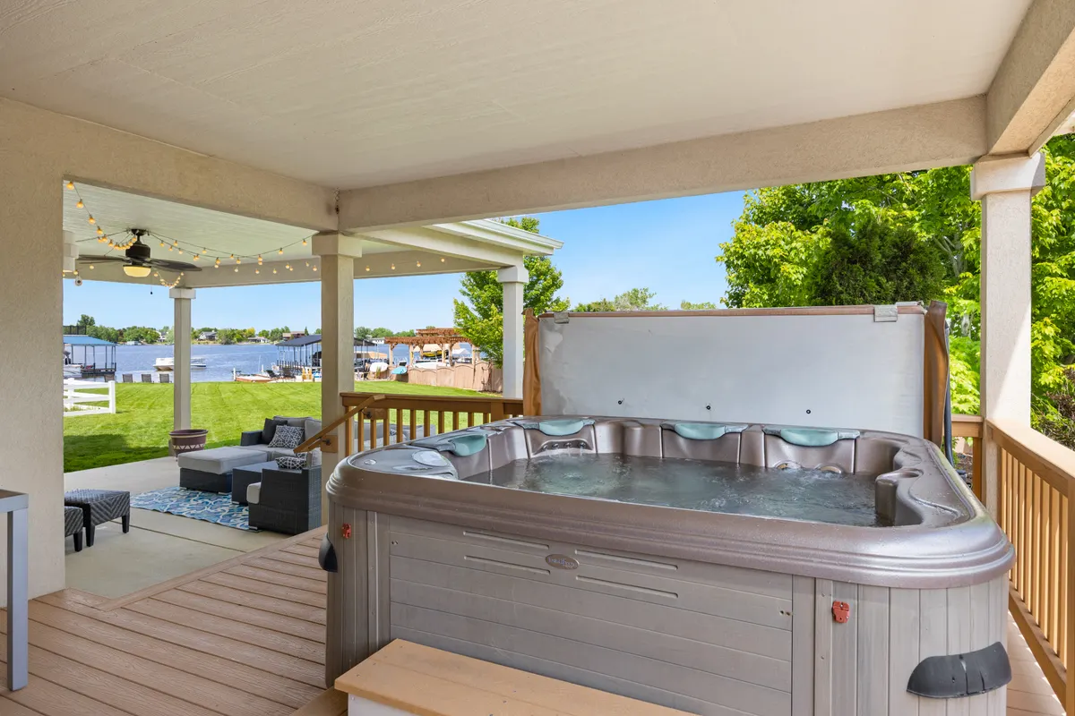 Patio exterior con un jacuzzi de lujo con vistas a un lago tranquilo
