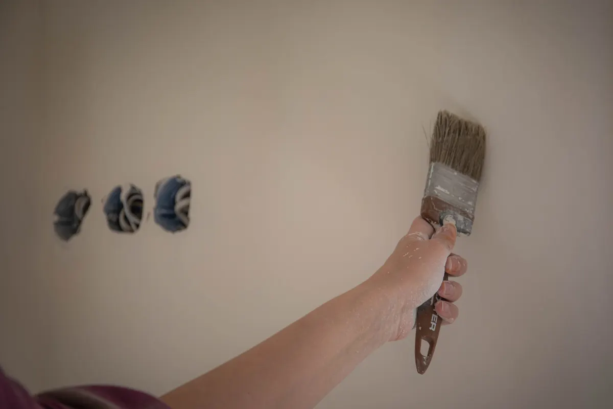Persona pintando una pared con una brocha durante la renovación de una casa