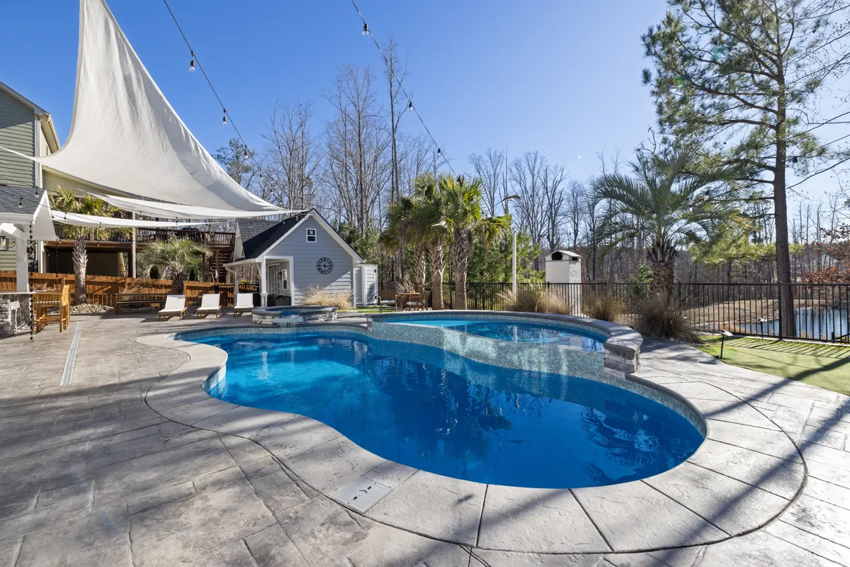 Piscina de jardín con tarima y palmeras en un día soleado