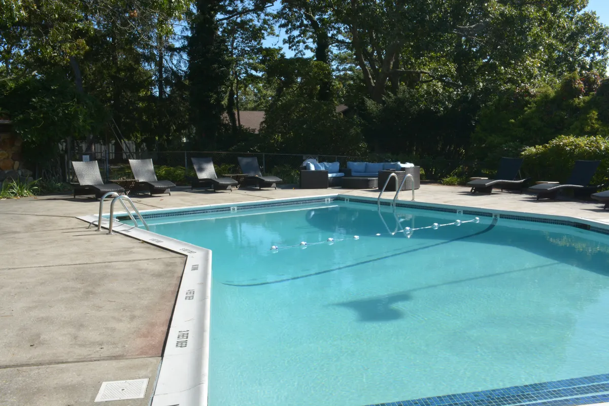 Piscina exterior con tumbonas junto a una vivienda con jardín