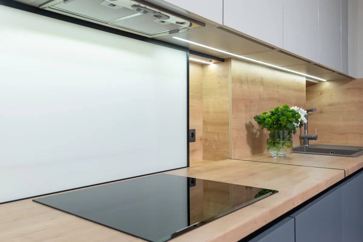 Placa de cocina empotrada bajo la campana extractora y los armarios, con un jarrón de flores