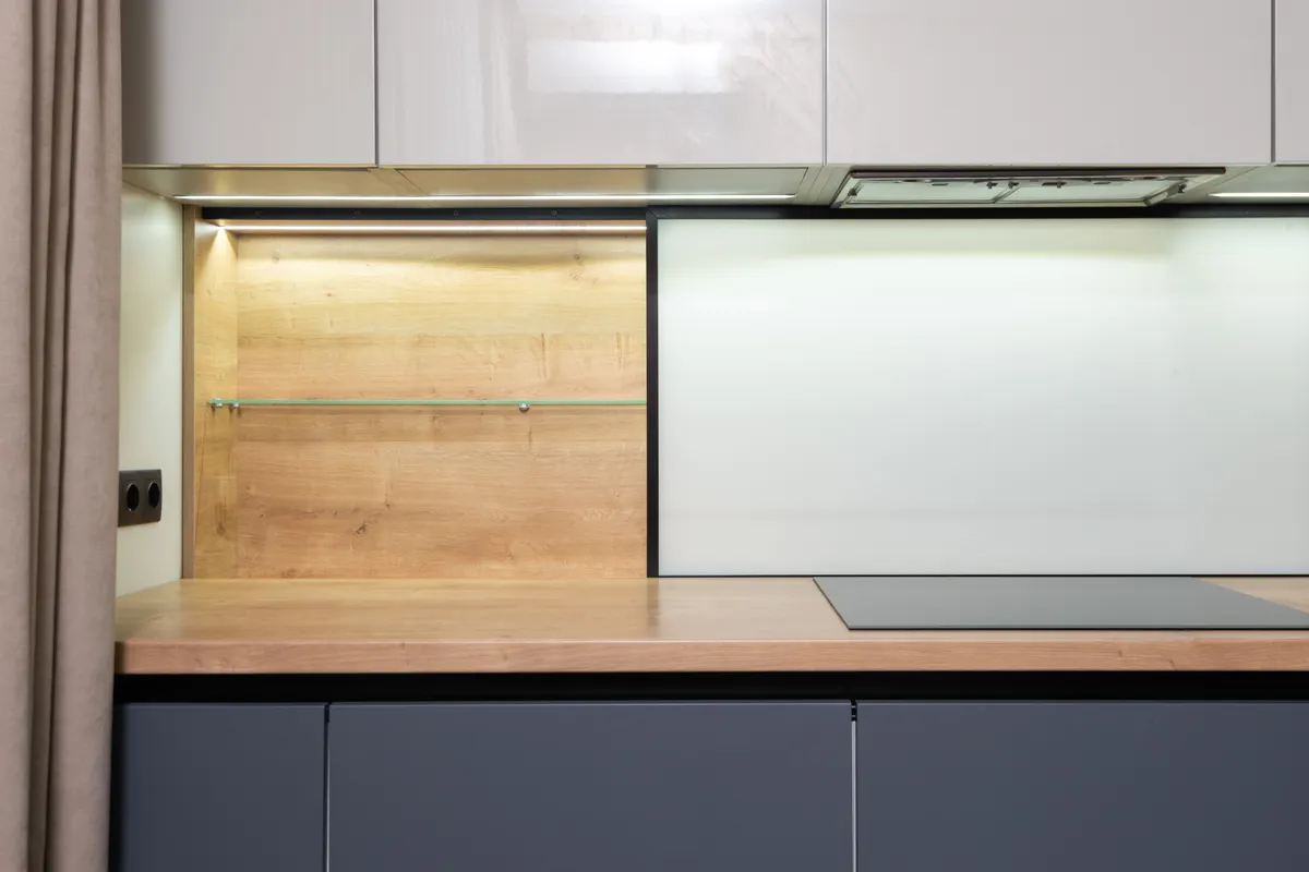 Placa de cocina integrada en una encimera de madera bajo un armario con campana