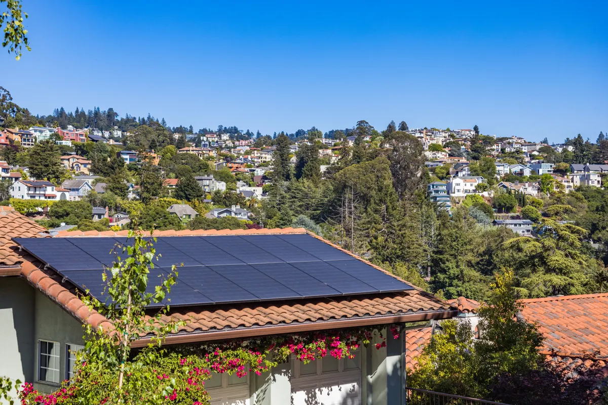 Placas solares en una vivienda rodeada de vegetación bajo un cielo azul y soleado