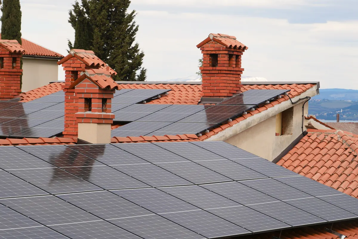 Placas solares sobre los tejados de teja de varias casas con chimeneas