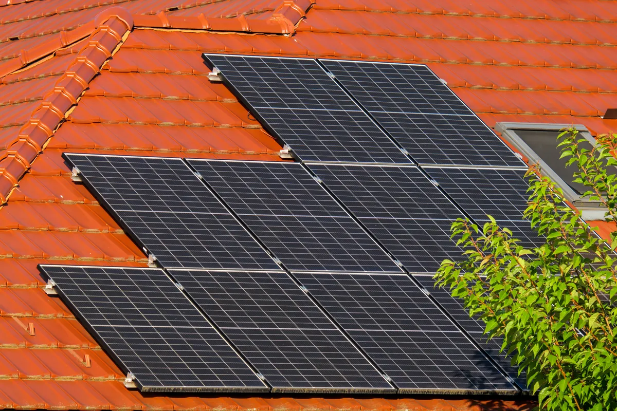 Placas solares sobre un tejado de tejas rojas en primer plano