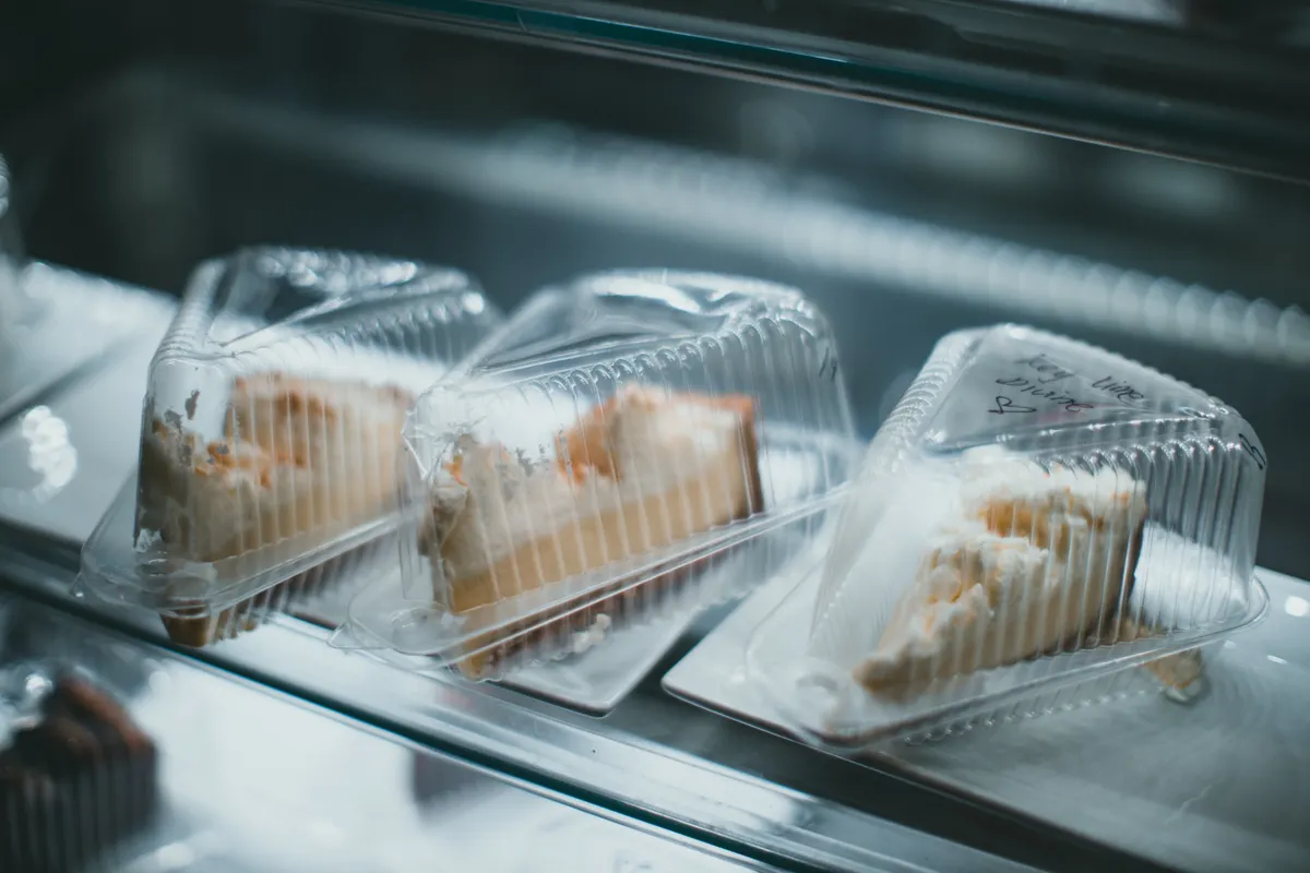 Porciones de tarta de queso en envases dentro de una vitrina refrigerada