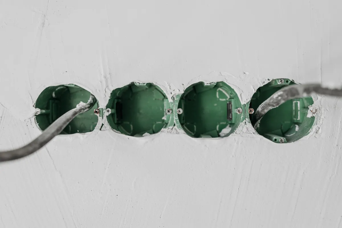 Primer plano de cajas eléctricas verdes y cableado instalados en una pared