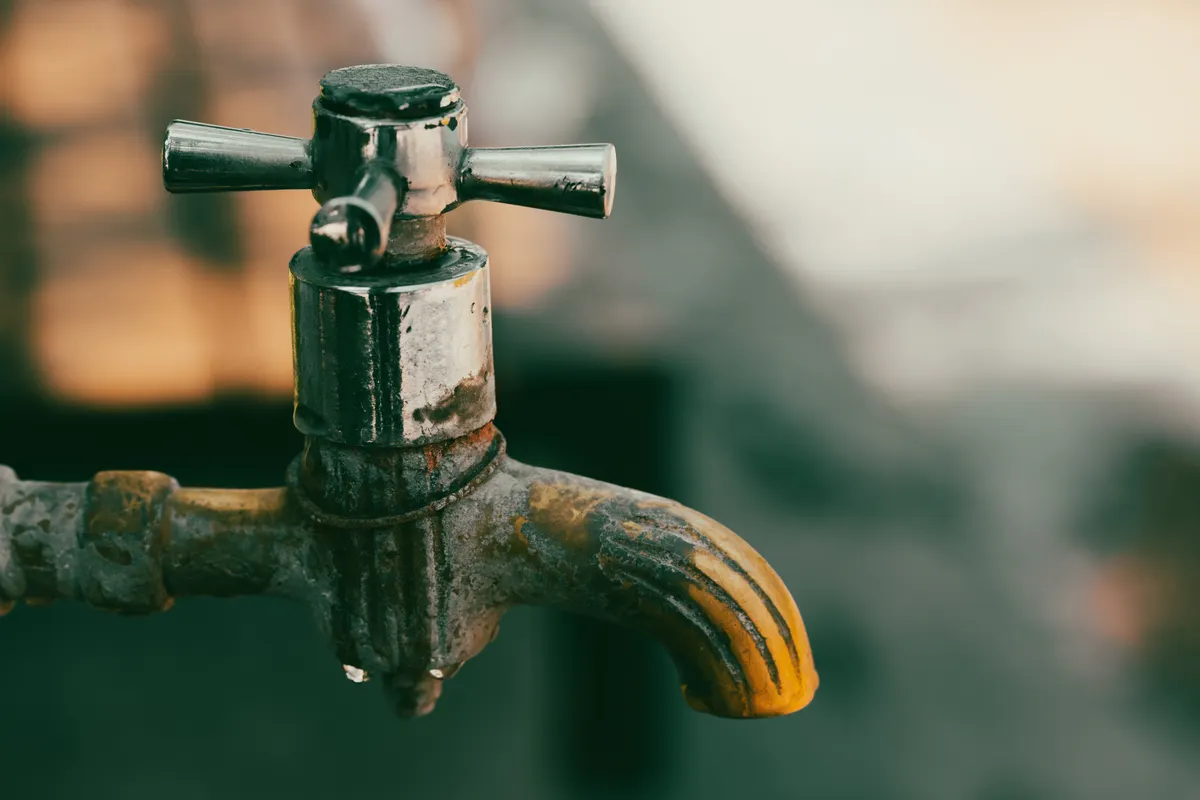 Primer plano de un grifo metálico de aspecto rústico con gotas de agua
