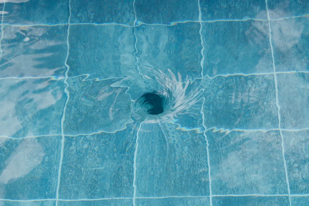 Remolino de agua junto al desagüe de una piscina de azulejos