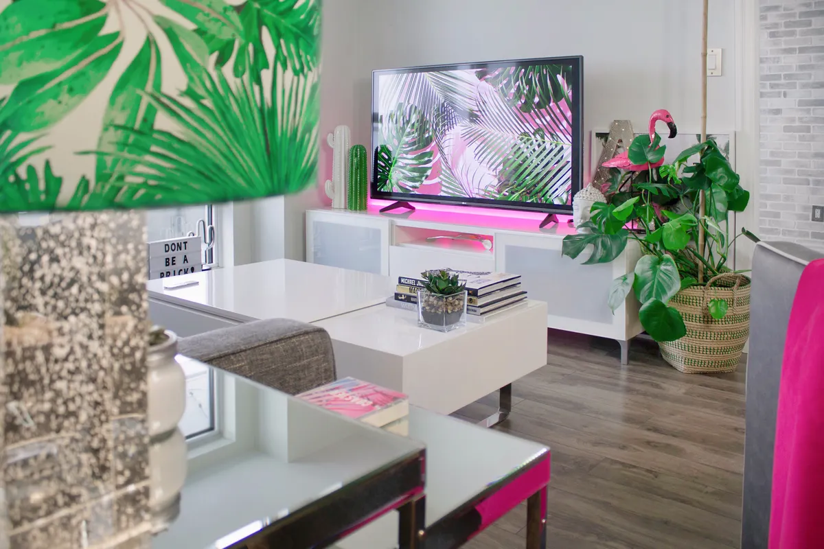 Salón con decoración tropical, plantas y un televisor moderno