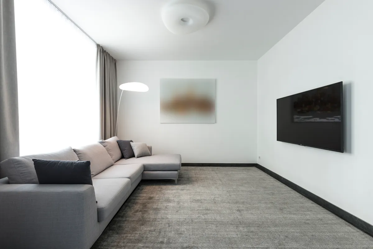 Salón contemporáneo con sofá modular gris y televisor de pared