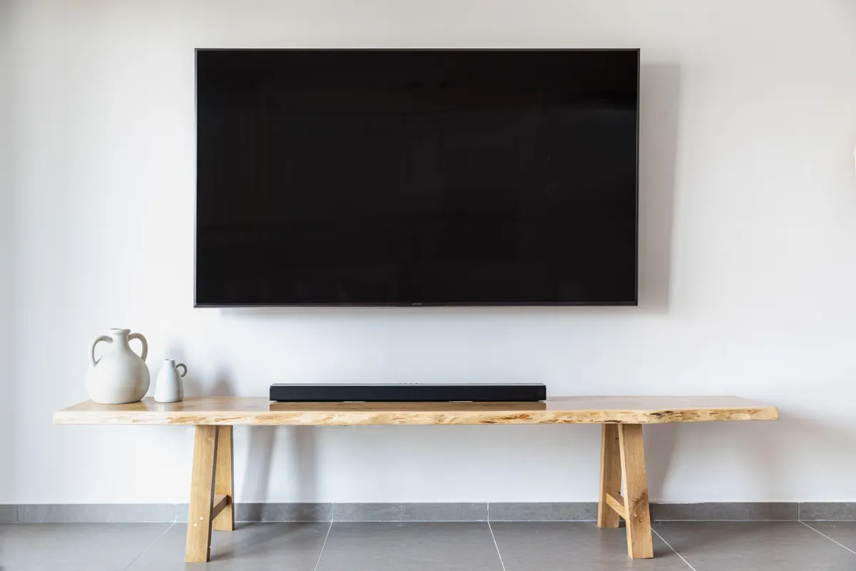 Salón minimalista con televisor plano colgado en la pared y una consola de madera