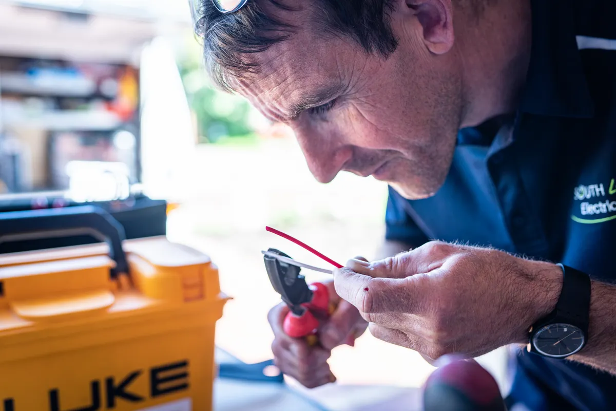 Técnico concentrado trabajando en un cableado con herramientas en un taller