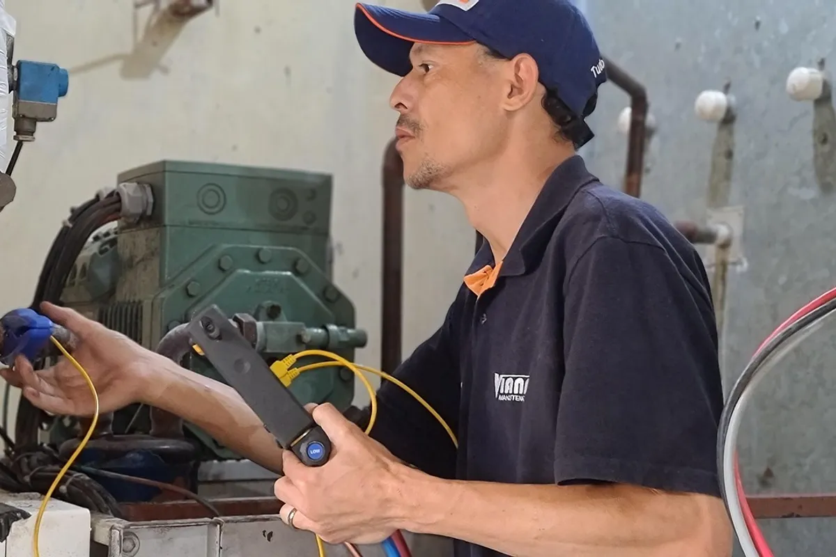 Técnico frigorista midiendo presiones con manómetros junto al compresor de un equipo de frío