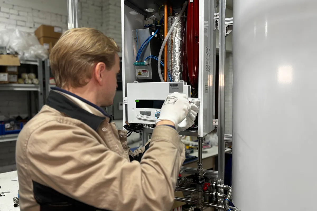 Técnico instalando o reparando un equipo de calefacción en un taller