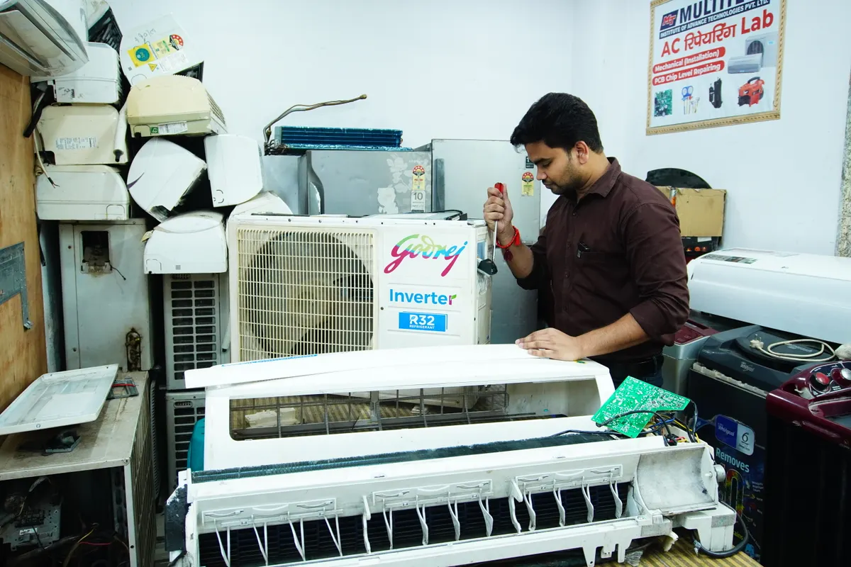 Técnico reparando un equipo de aire acondicionado en un taller