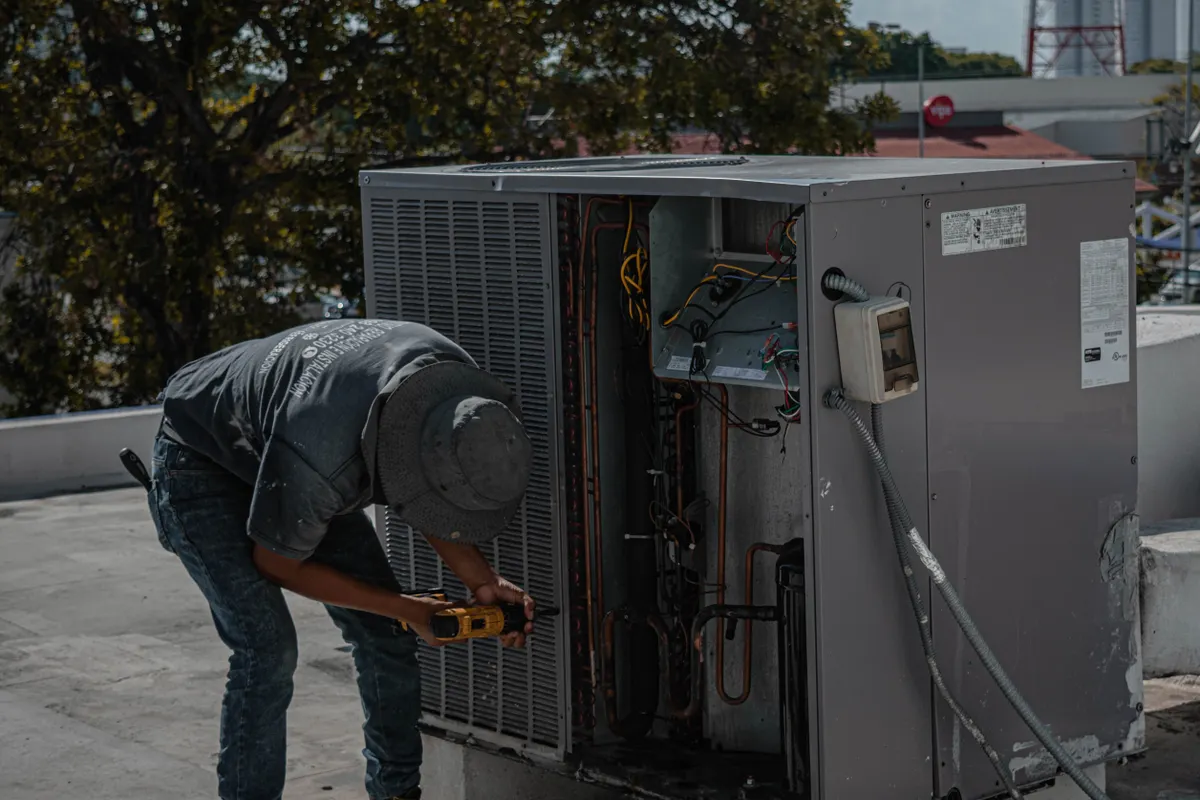 Técnico reparando una unidad de aire acondicionado en una azotea