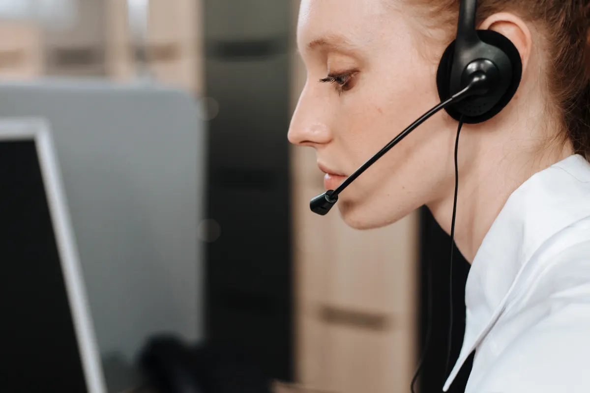 Teleoperadora con auriculares trabajando en su mesa, en primer plano