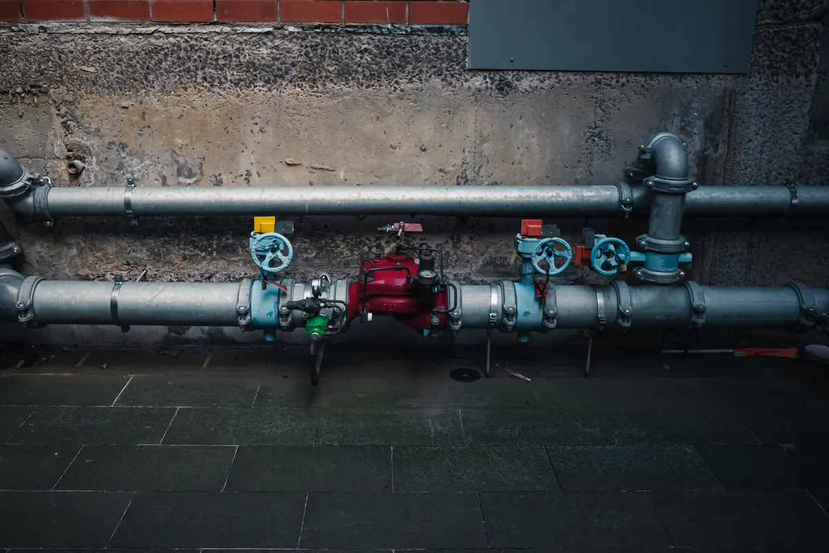 Tuberías industriales con válvulas de colores en una pared con textura