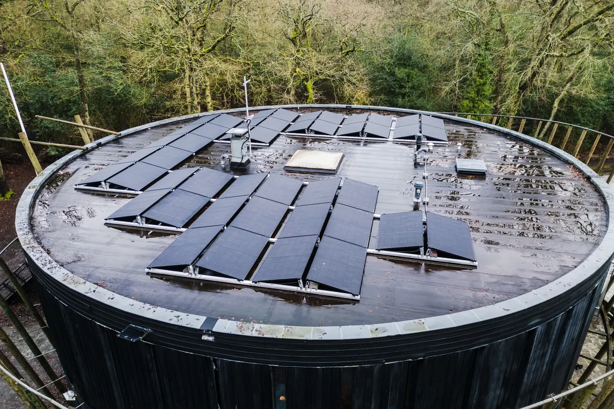 Vista aérea de un tejado redondo con placas solares rodeado de árboles