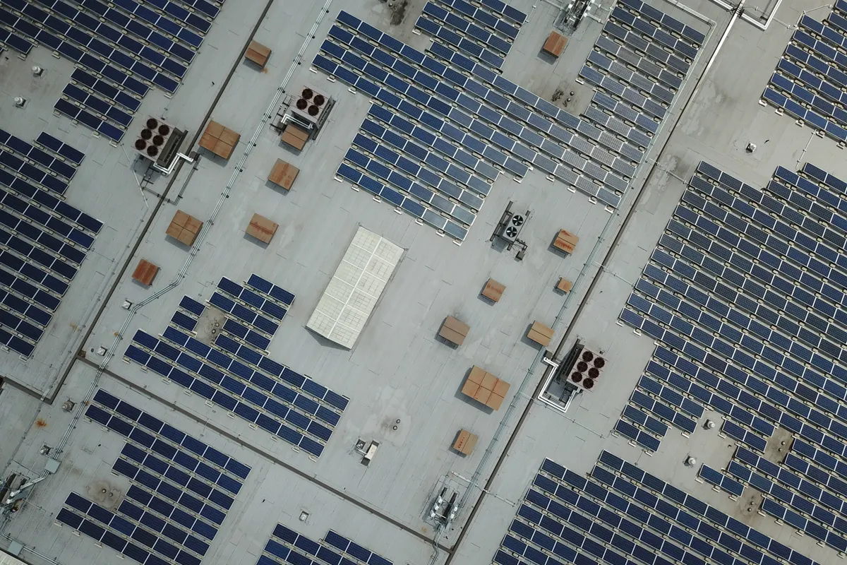 Vista aérea de una gran instalación de placas solares en la cubierta de una nave industrial
